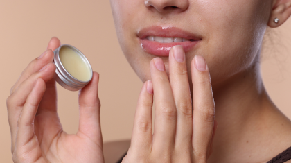 Close-up van een persoon die lippenbalsem op de lippen aanbrengt.