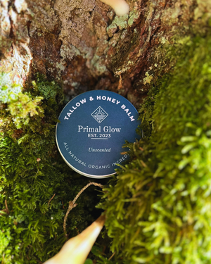 Primal Glow tallow en honing hydraterende balsem van 100 ml in een natuurlijke groene omgeving.